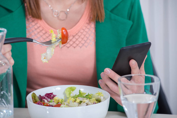 young  woman eating salad and phone - Фото, изображение