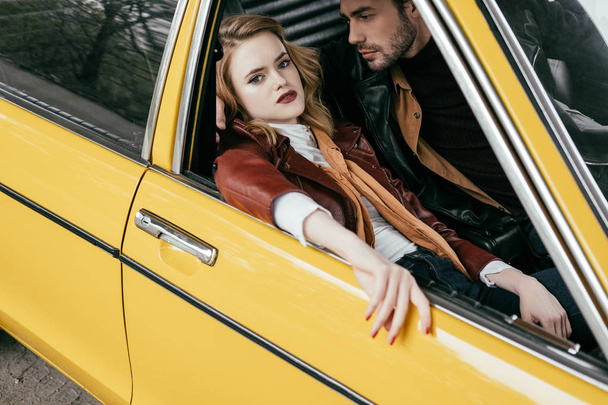 high angle view of beautiful stylish girl looking at camera while sitting with boyfriend in car - Foto, immagini