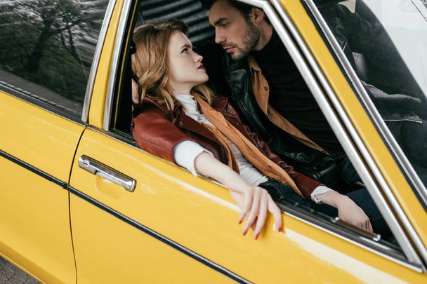 high angle view of stylish young couple in love looking at each other in yellow car - Φωτογραφία, εικόνα