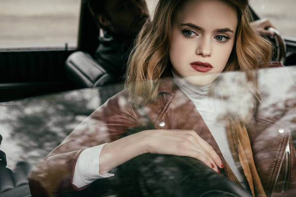 beautiful pensive young woman looking through car window while boyfriend driving car - Foto, afbeelding