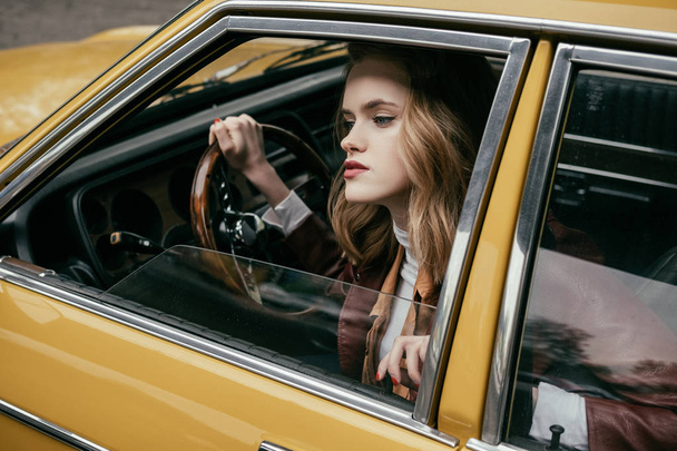 attractive stylish girl sitting in tero car and looking away - Фото, зображення