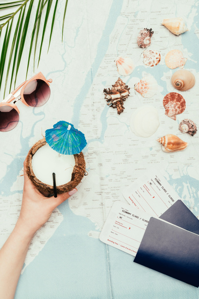 przycięte zdjęcie kobiety z koktajlem kokosowym i bilety lotnicze na mapie podróży - Zdjęcie, obraz