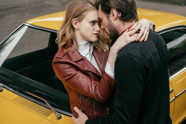 beautiful sensual young couple hugging near yellow old-fashioned car - Foto, Imagen