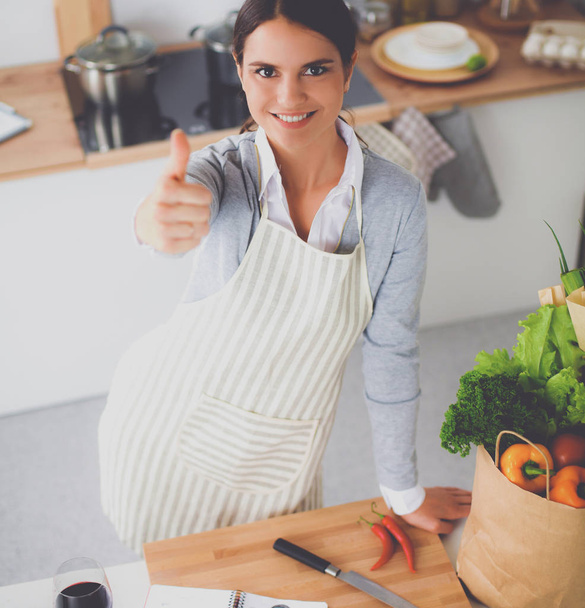 Woman in apron standing on the desk with grocery bagand showing ok  - Foto, immagini