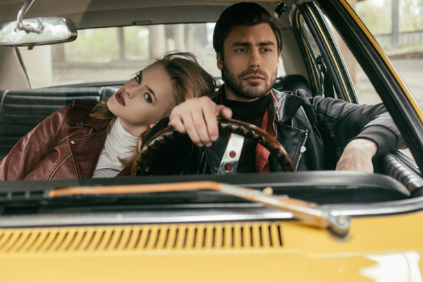 beautiful stylish young couple in leather jackets sitting together in classic car - Photo, Image