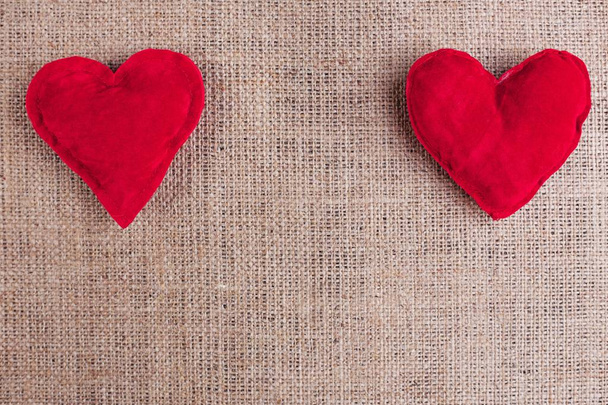 Valentijnsdag achtergrond met twee rode stof harten op sackclot - Foto, afbeelding