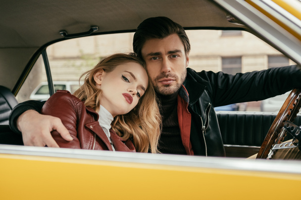 beautiful stylish young couple embracing and looking at camera in car  - Valokuva, kuva