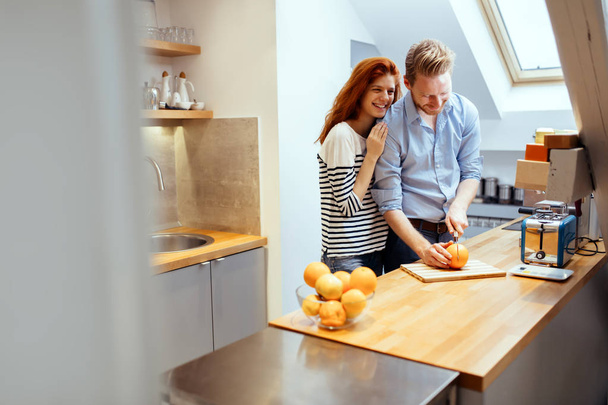 Happy couple making organic juice in kitchen and smiling - Фото, изображение