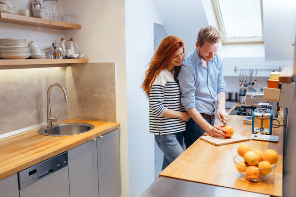 Feliz pareja haciendo jugo orgánico en la cocina y sonriendo
 - Foto, Imagen