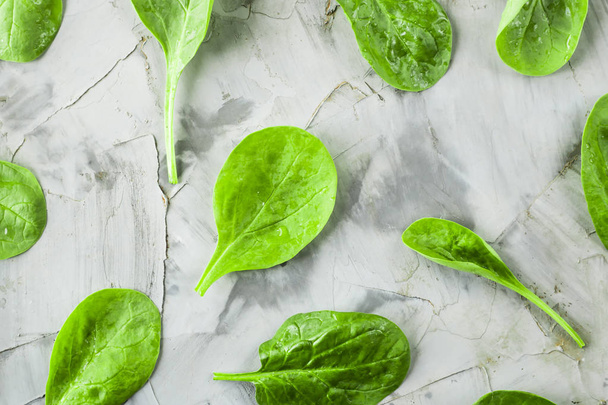 Вимиті листя шпинату розкидані на сірому столі. Свіже зелене листя для приготування здорових страв. Тло
 - Фото, зображення