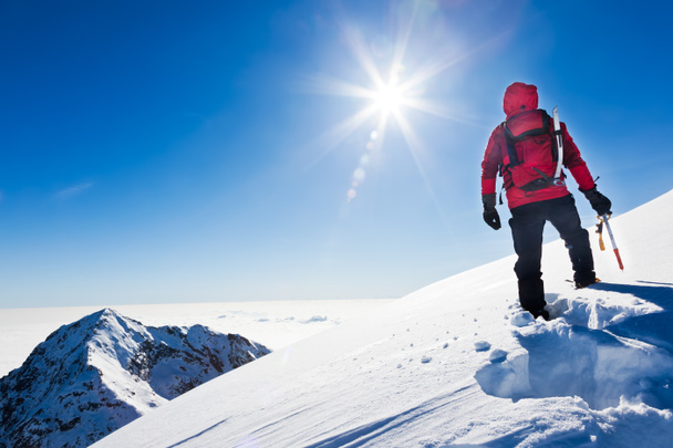 Hegymászó eléri a tetején egy havas hegy, egy napsütéses téli di - Fotó, kép