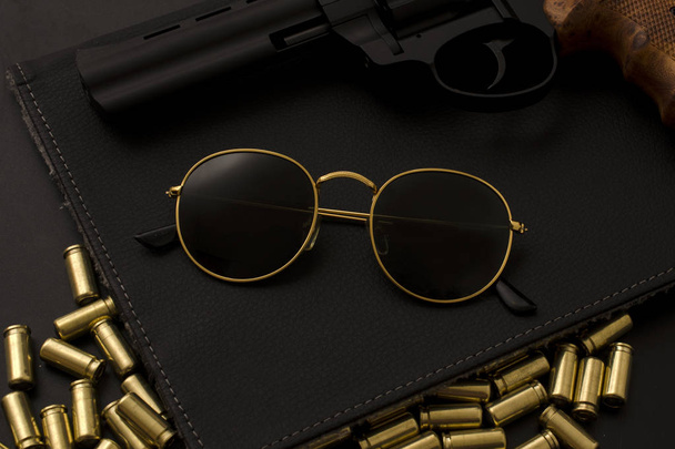 napszemüveg és egy fegyver, a fekete háttér - Fotó, kép
