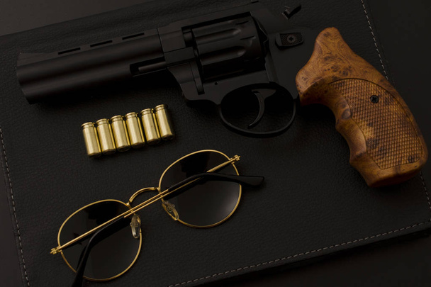 солнцезащитные очки и пистолет на черном фоне
 - Фото, изображение
