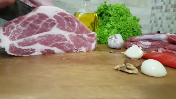 Schneiden von saftigen und köstlichen Schweinehals auf dem Hintergrund von Butter, Walnüssen, Zwiebeln, Gemüse und Pfeffer - Filmmaterial, Video