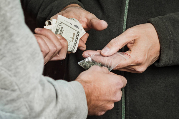 Χέρι τοξικομανής με χρήματα αγοράζει μια δόση μαριχουάνα από ένα φάρμακο - Φωτογραφία, εικόνα