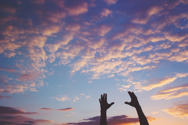 Σιλουέτα του αρσενικό χεριών ενάντια συννεφιασμένο ουρανό στο ηλιοβασίλεμα - Φωτογραφία, εικόνα