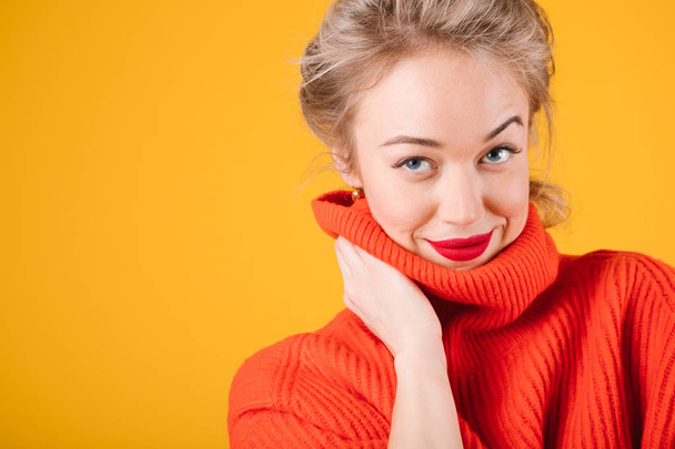 tricky seductive flirting look woman in red jumper on yellow background - 写真・画像