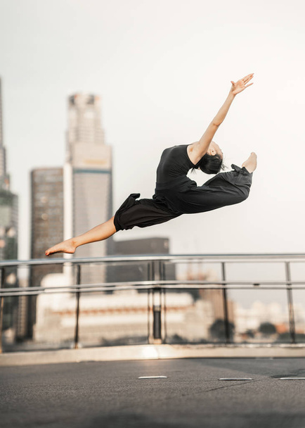 Passion... Young woman athlete performs a perfect leap high up, on a bridge  with background of skyscrapers  - Фото, зображення