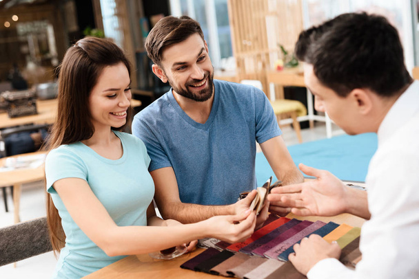 Two men and a woman are discussing the purchase of new furniture. This is a young family who came to the store. They are in a good mood. - 写真・画像