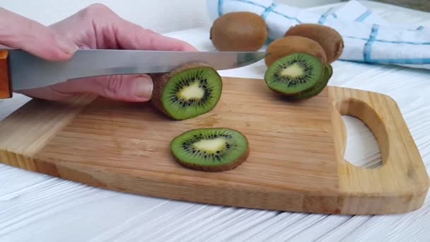 knife cuts kiwi on a wooden slow-motion shot - Footage, Video