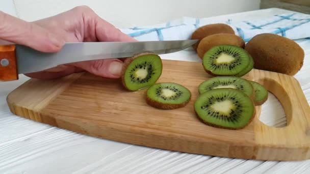 knife cuts kiwi on a wooden slow-motion shot - Footage, Video