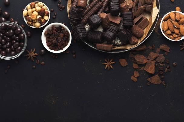Top näkymä suklaa ja pähkinät mustalla pohjalla
 - Valokuva, kuva