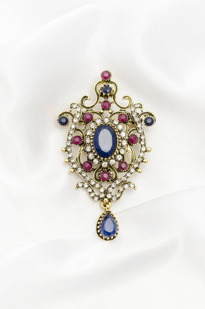 Vintage gold brooch with precious stones on white silk - Photo, Image