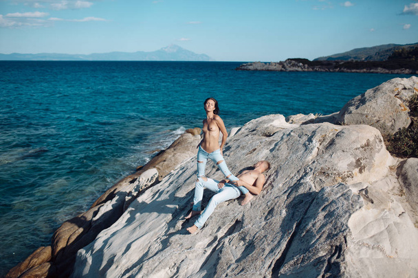 Fashion and beauty. Summer holidays and paradise travel vacation. Sexy woman and man have sex games. Love relations of naked couple at sea water. Couple in love with sexy body relax on stone - 写真・画像