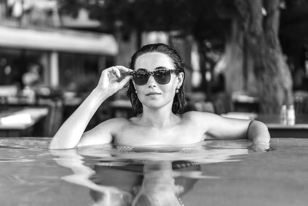 Pretty brunette girl sunbathing at the swimming pool - Fotoğraf, Görsel