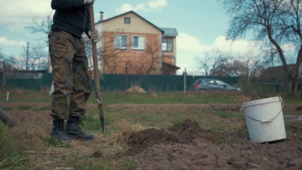 мужчина копает землю сапогом - Кадры, видео