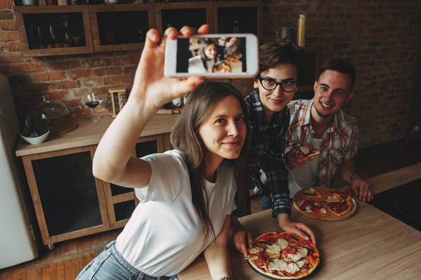 Home pizza party. Friends have fun and eat pizza at home kitchen - Foto, Imagen
