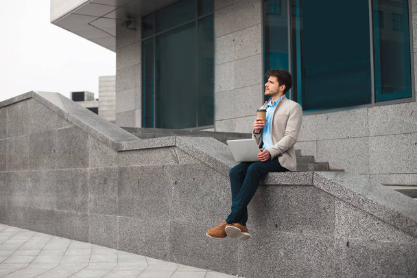 C'est l'heure de se reposer ! Rêver jeune homme décontracté intelligent assis à l'extérieur et boire du café à emporter, tout en étant à l'aéroport et en attendant son vol
. - Photo, image