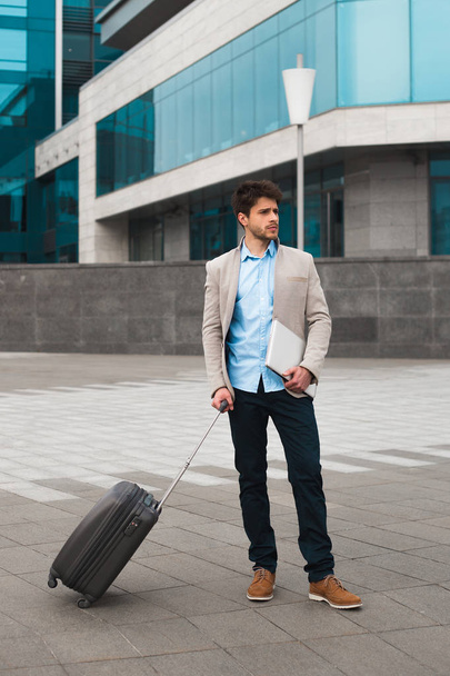 ¡Viaje de negocios! Atractivo hombre de negocios inteligente que lleva la maleta mientras camina a bordo del avión en el aeropuerto
. - Foto, imagen