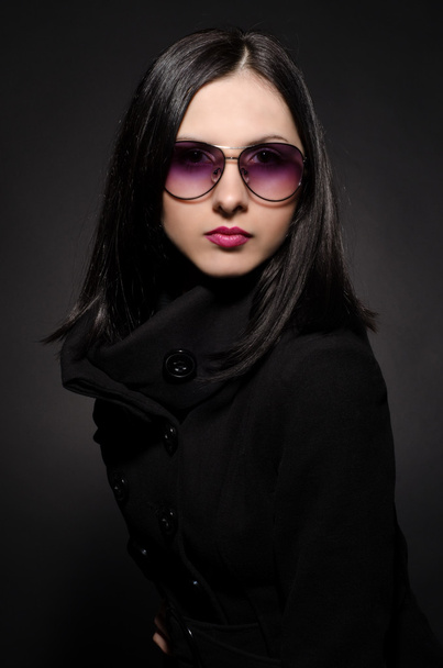 Portrait of a beautiful young woman in sunglasses on black background - Foto, afbeelding