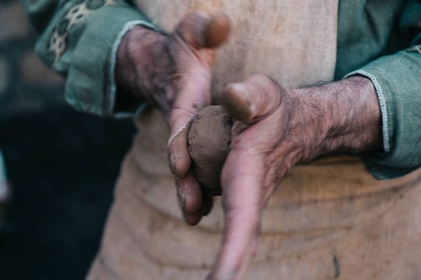 Potter works with clay, craftsman hands close up, kneads and moistens clay - Φωτογραφία, εικόνα
