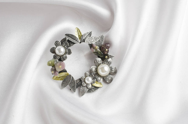 καρφίτσα με λουλούδια και μαργαριτάρια σε λευκό μετάξι γύρο - Φωτογραφία, εικόνα
