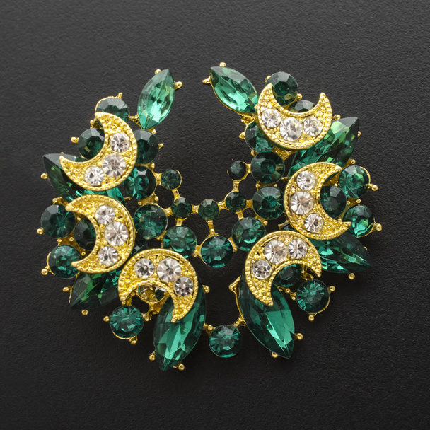 golden brooch with emeralds and diamonds isolated on black - Photo, Image