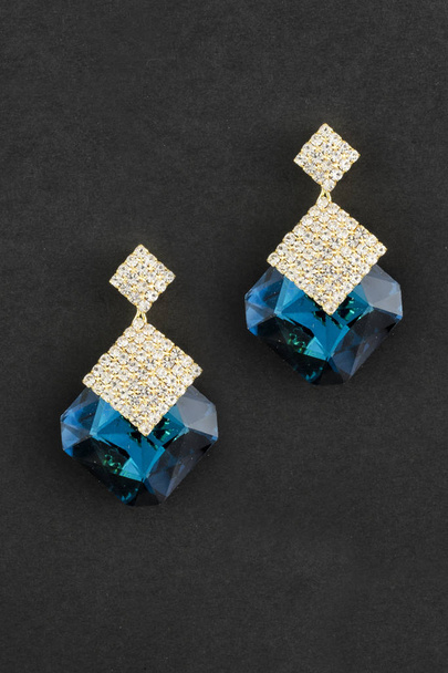 gold earrings with big blue stones isolated on black - Photo, Image