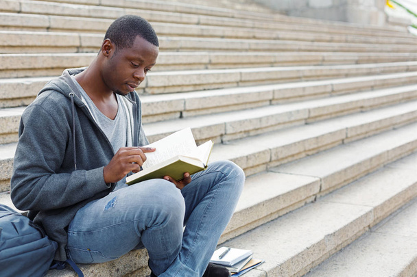 Young man reading book in campus copy space - Φωτογραφία, εικόνα