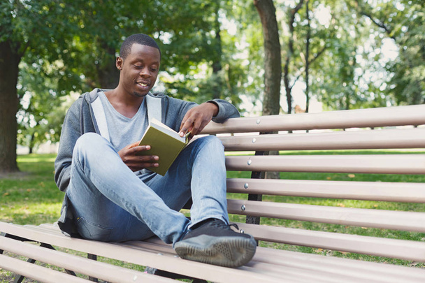 Young man reading book in park copy space - Foto, Imagen