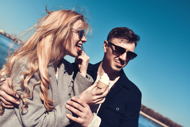 Happy romantic caucasian couple in sunglasses. Funny girl eat the ice cream - Zdjęcie, obraz