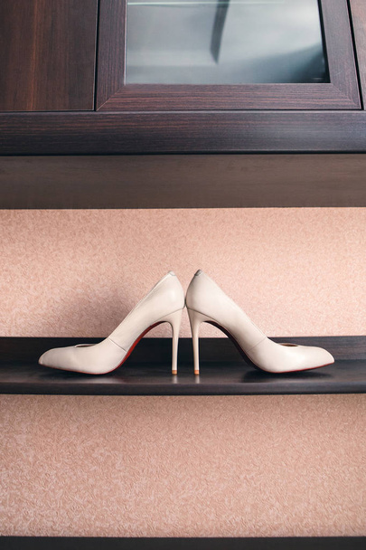 une paire de chaussures blanches à talons hauts se tient sur un banc près de la maison
 - Photo, image