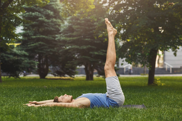 Man lying down doing lower abs exercise outdoors - Photo, Image