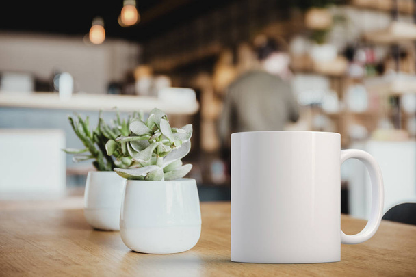 White coffee Mug Mockup set-up in a cafe, next to cactus plants and with blurred background. Great for overlaying your custom quotes and designs for selling mugs. - Foto, Bild