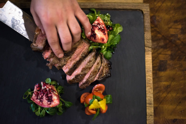 top view of Chef hands in hotel or restaurant kitchen serving beef steak with vegetable decoration - Fotó, kép