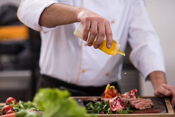 Chef male hands finishing serve steak plate with oil - Fotografie, Obrázek