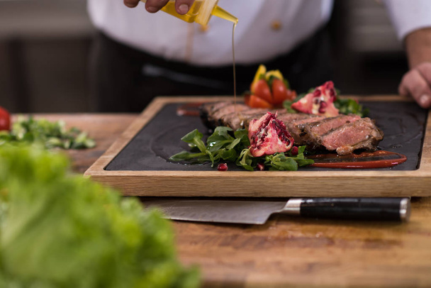 Chef male hands finishing serve steak plate with oil - Foto, Bild