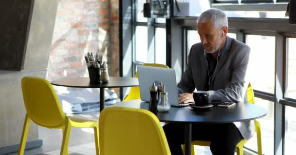 Mature businessman having coffee while using laptop in hotel 4k - Felvétel, videó