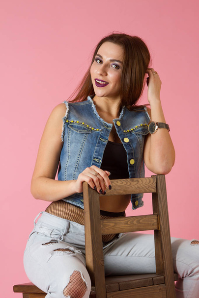 girl in a jeans suit is sitting on a bar stool - Foto, Imagen