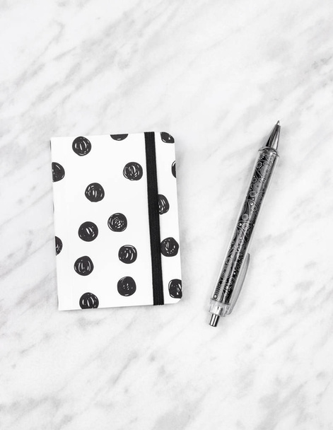 schwarz-weißes Tagebuch und Stift auf Marmorhintergrund - Foto, Bild